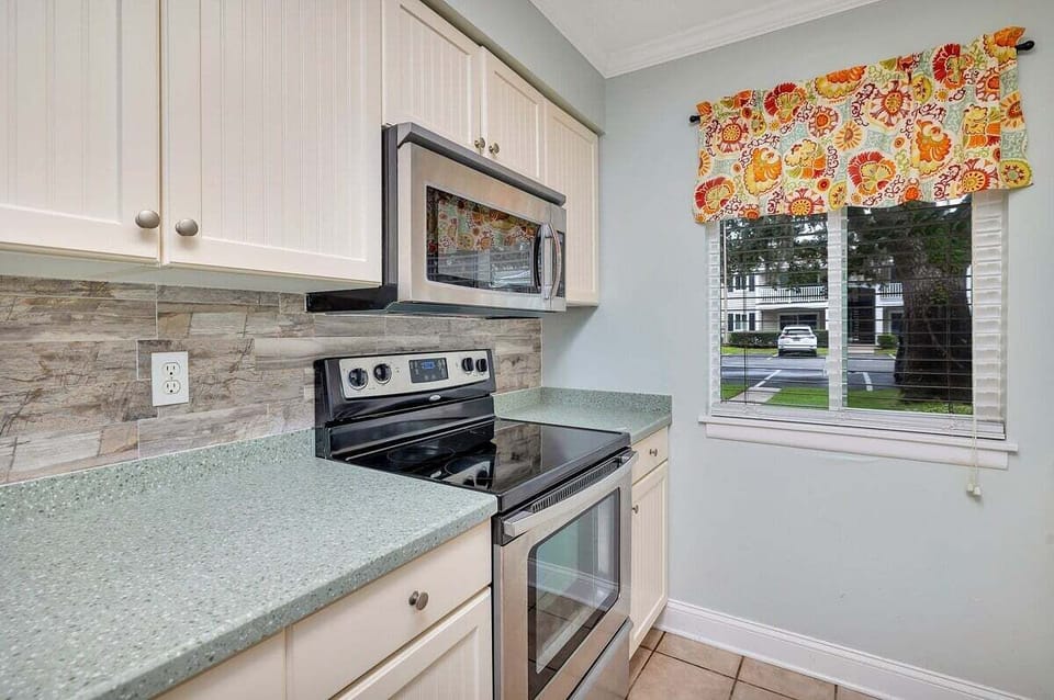 Ocean Walk N4 - Kitchen with white cabinets, stainless appliances, and floral valance