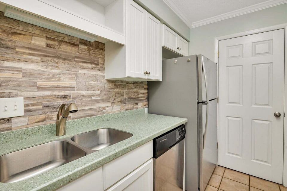 Ocean Walk N4 - Kitchen with white cabinets, stainless sink, and stone backsplash