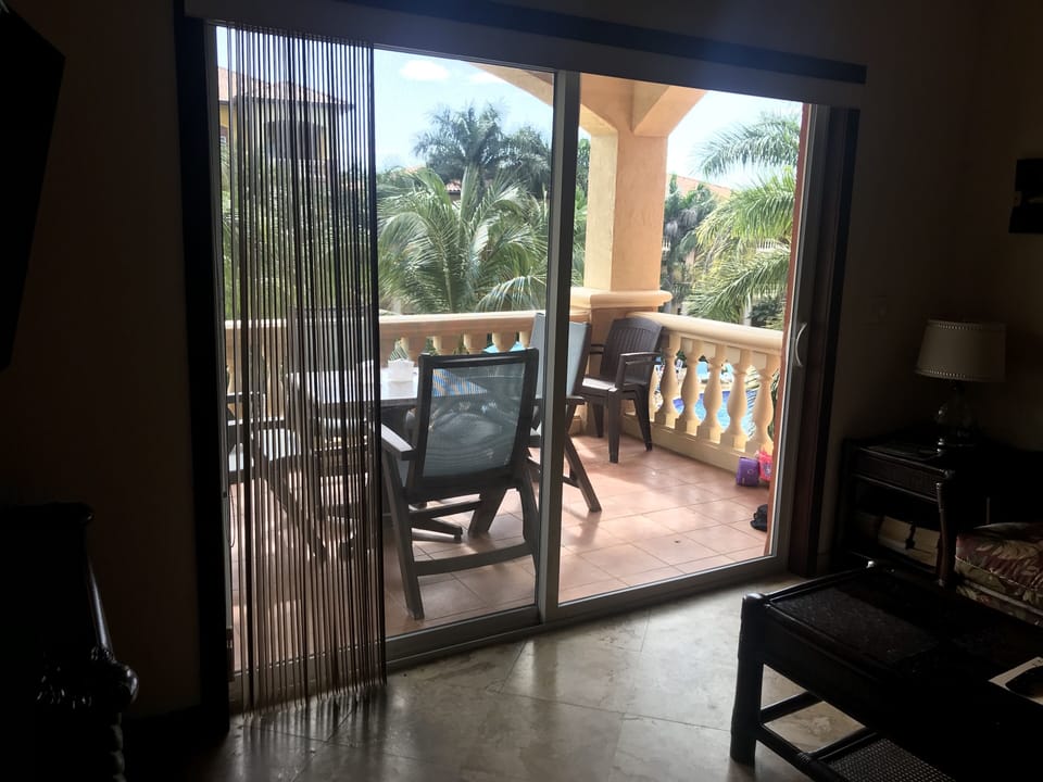 View from living room  to our main balcony view of the pool, green & ocean