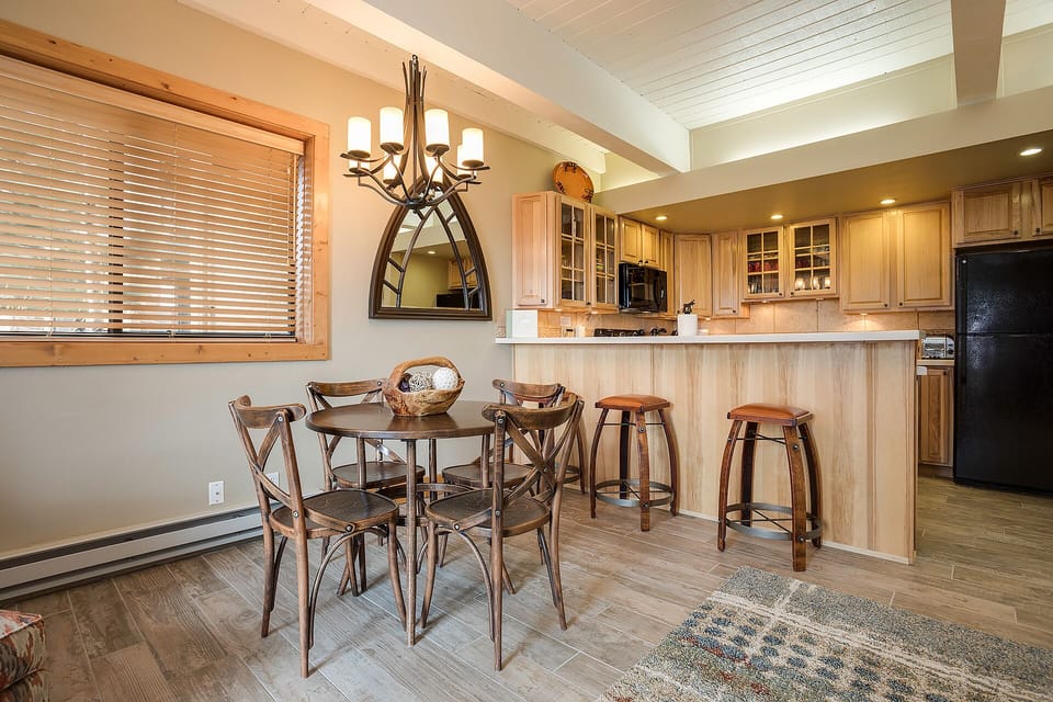 Gather around your rustic dining table while breakfast sizzles in the fully-equipped kitchen, where warm wood and modern amenities create the perfect mountain retreat.