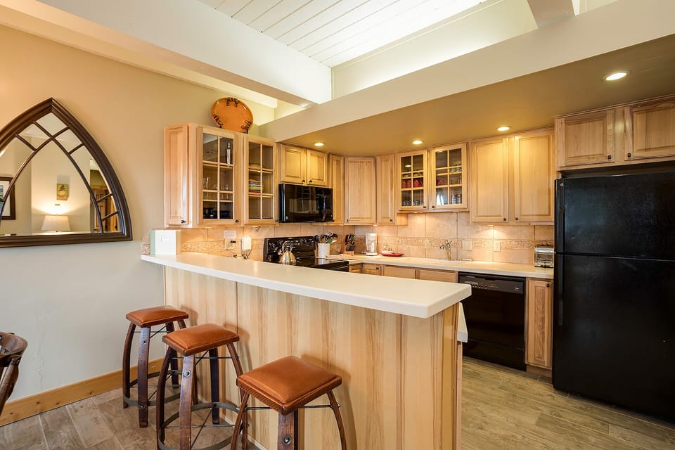 Cook your favorite meals in this warm, well-equipped kitchen featuring beautiful wood cabinets, modern appliances, and a convenient breakfast bar.