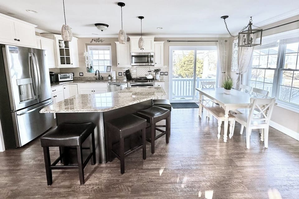 Enjoy a bright and spacious kitchen equipped with modern stainless steel appliances and a large granite island for casual seating. The adjacent dining table offers a lovely spot for family meals, with sliding glass doors that lead right out to the deck.