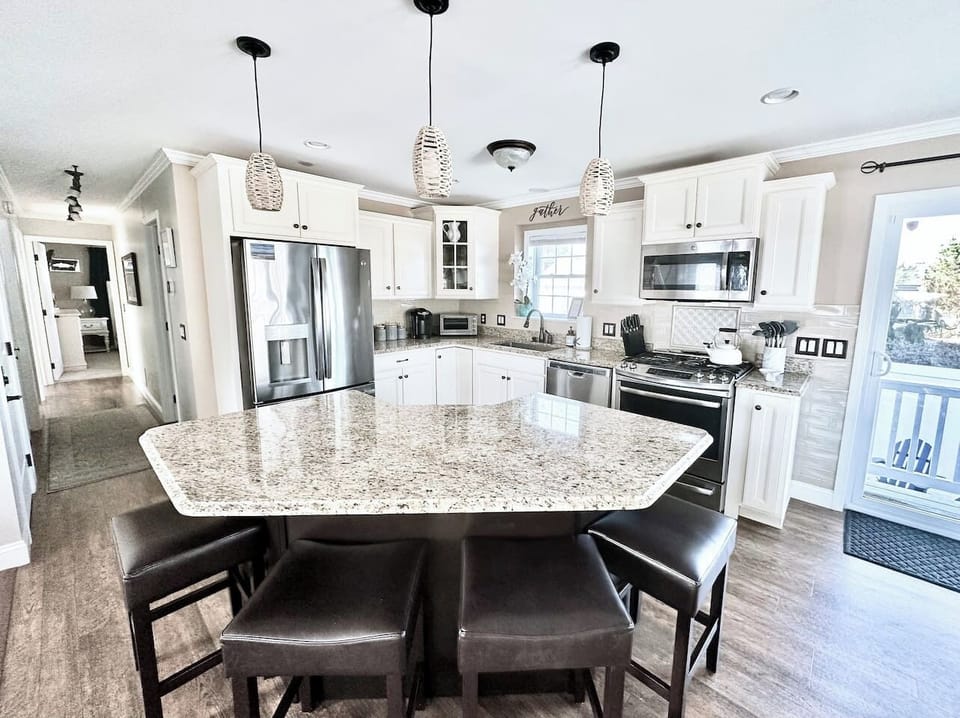 Gather around the spacious granite island, complete with seating for four. This fully equipped kitchen features stainless steel appliances and ample counter space, making it an ideal spot for morning coffee or casual group meals.