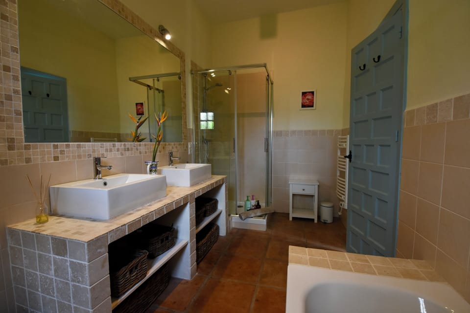 en-suite bathroom with full bath, separate shower, twin sinks, and toilet.