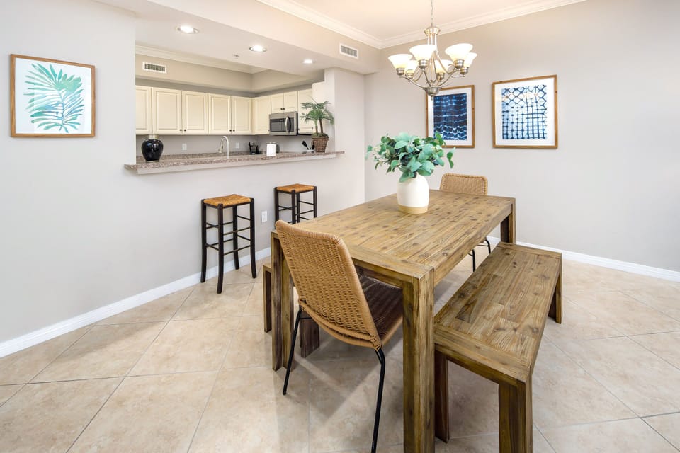 Dining room table, chairs, & benches in between the kitchen bar & living room. 