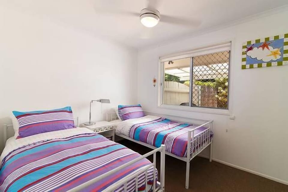 Twin bedroom with mirrored built-ins, fly screen, view to pool, blackout blinds