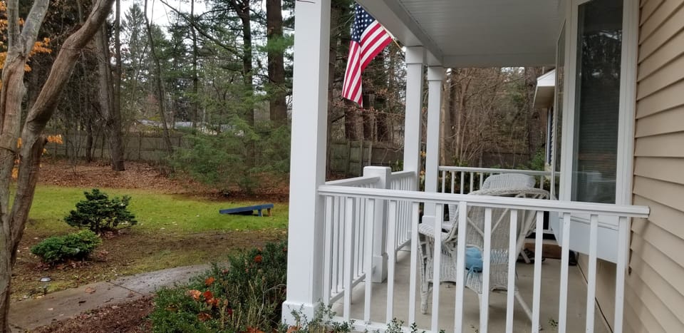 Front porch with 2 chair overlooking cornhole game