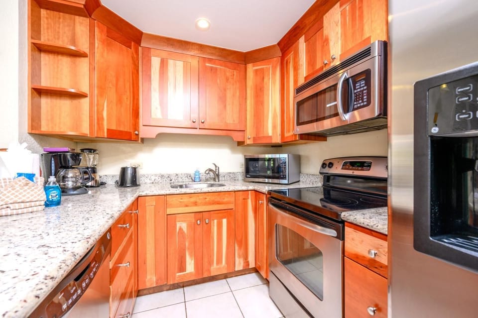 Modern granite kitchen with stainless appliances and warm wood cabinetry.