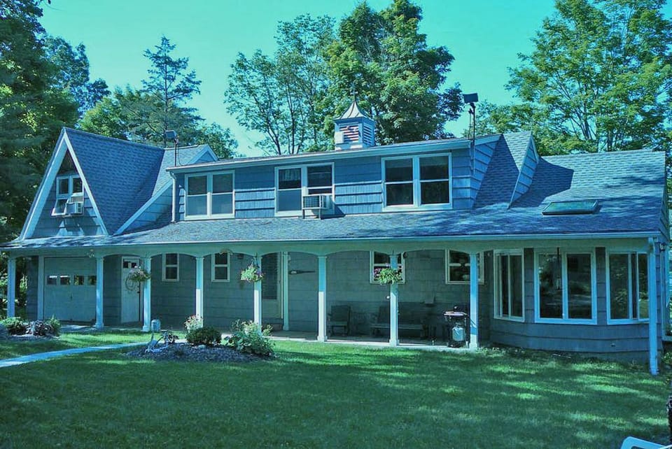 Front yard of The Lake House in summer shaded by large elm tree