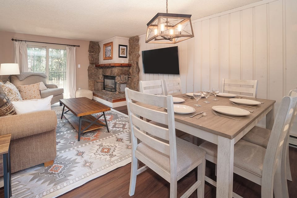 Your open-concept living space invites gatherings around the dining table, while the stone fireplace creates cozy evenings.