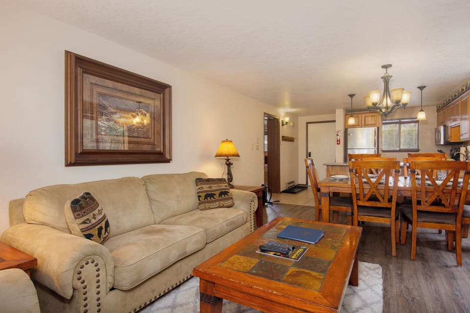 Sink into plush seating where warm mountain artwork and rustic wood create your perfect retreat after adventure-filled days.