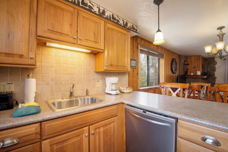 Your fully equipped kitchen awaits with warm wood cabinetry, granite counters, and stainless appliances—perfect for preparing mountain meals together.