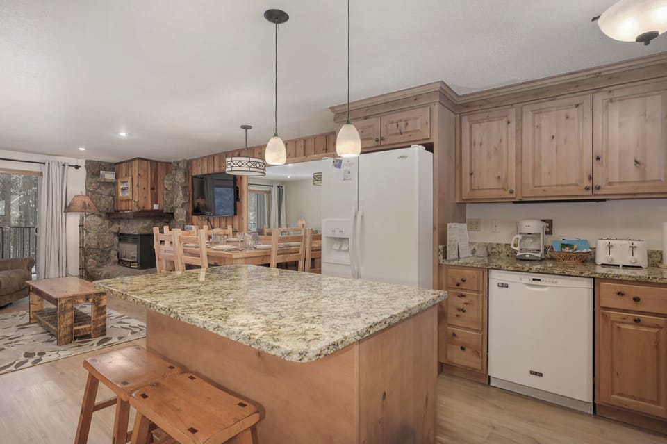 Your mountain retreat kitchen features granite countertops, knotty pine cabinets, and a cozy stone fireplace backdrop for memorable family meals.