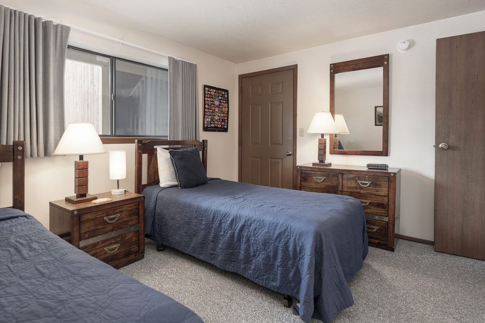Rest peacefully in your comfortable twin bedroom, featuring warm wood furnishings and soft lighting for the perfect night's sleep.