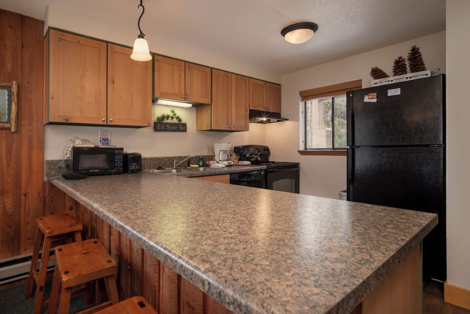 Your fully equipped kitchen features warm wood cabinets, granite counters, and modern appliances for preparing memorable meals together.
