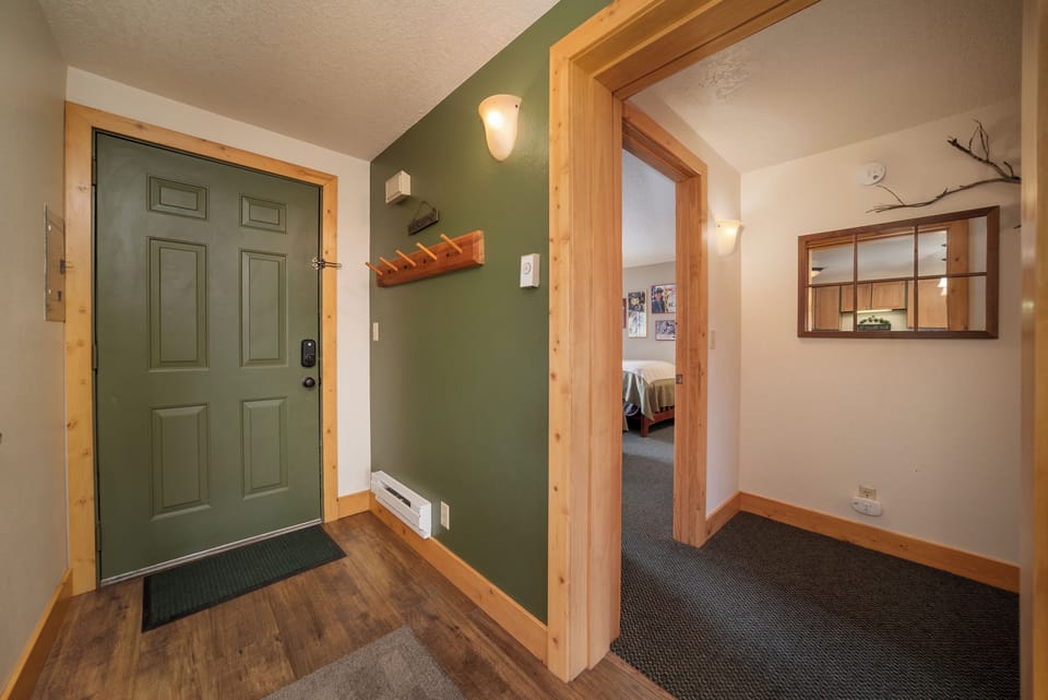 Step into your cozy mountain retreat through warm wood-framed entryway with rustic charm and thoughtful amenities.