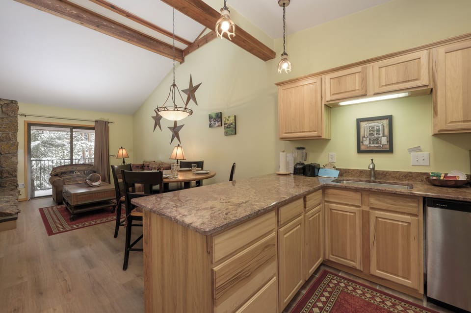 Your spacious mountain retreat features an open kitchen with granite counters, rustic beams, and cozy living area perfect for gathering.