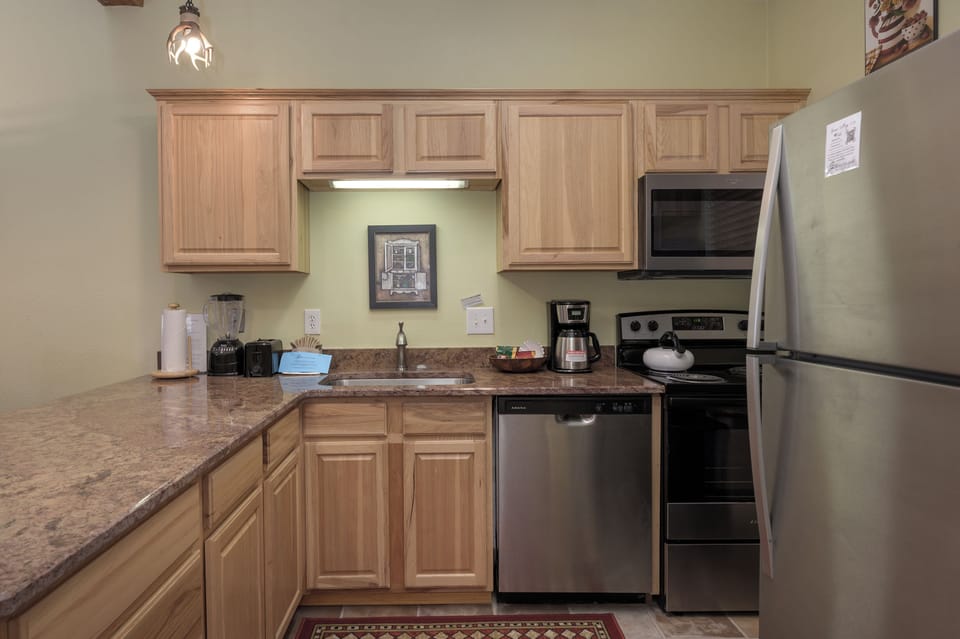 Your fully equipped kitchen awaits with granite counters, stainless appliances, and warm wood cabinets - everything you need for memorable meals.