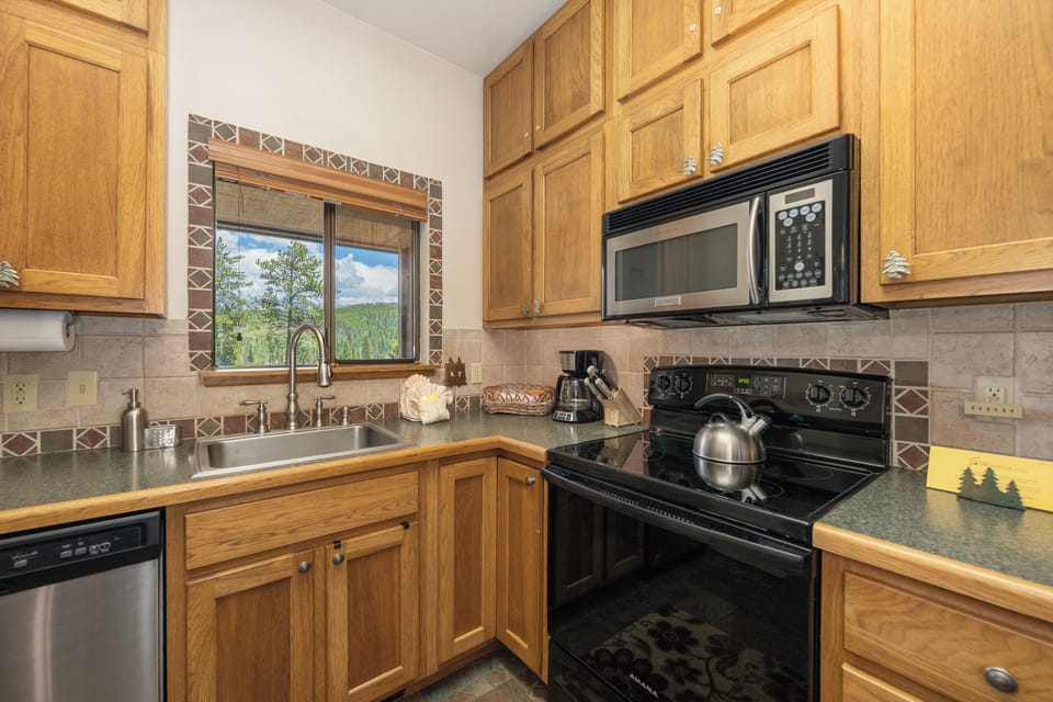 Your fully equipped kitchen features warm wood cabinets, modern appliances, and a window with scenic mountain views.