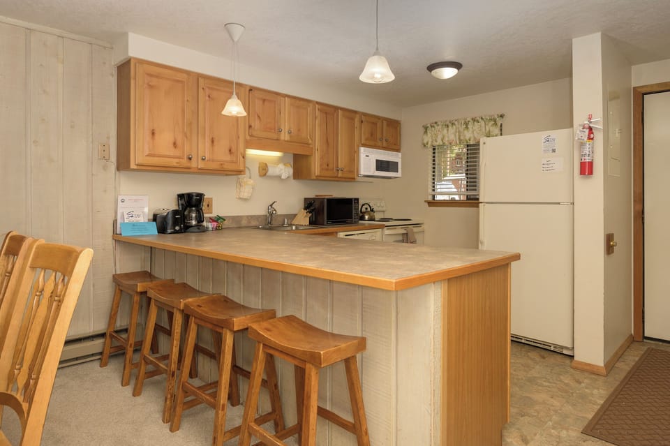 Your fully equipped kitchen features warm wood cabinets, granite counters, and a breakfast bar perfect for morning coffee or casual dining.