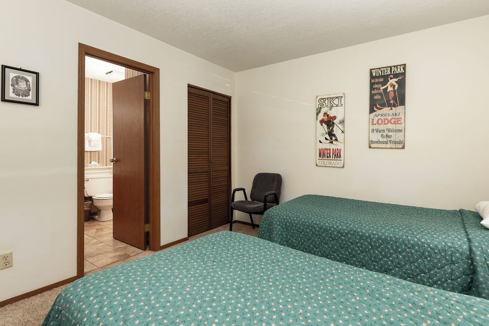 Cozy twin bedroom with vintage ski lodge charm, featuring comfortable beds and your own private bathroom for peaceful mountain getaways.