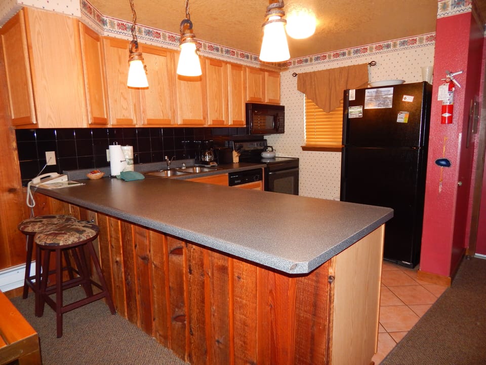 Your fully equipped kitchen features warm wood cabinets, modern appliances, and a spacious breakfast bar perfect for morning coffee.