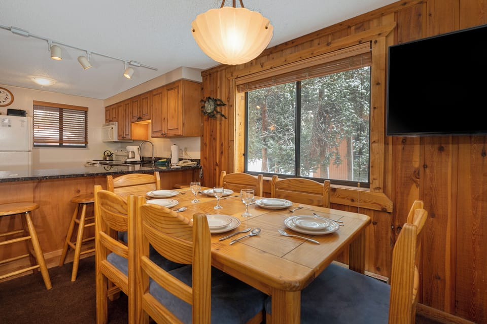 Gather around your warm wooden dining table, perfectly set for memorable meals with mountain views through the window.