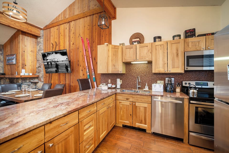 Your rustic alpine kitchen features granite counters, stainless appliances, and cozy wood accents perfect for preparing meals after skiing adventures.