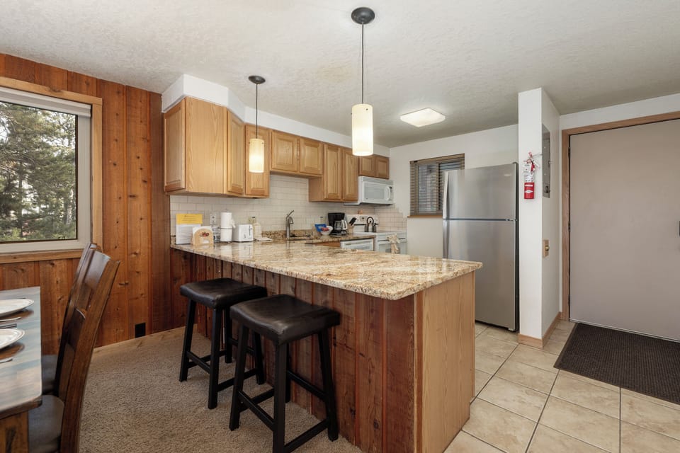 Your fully equipped kitchen features granite counters, modern appliances, and a breakfast bar where you can enjoy morning coffee.