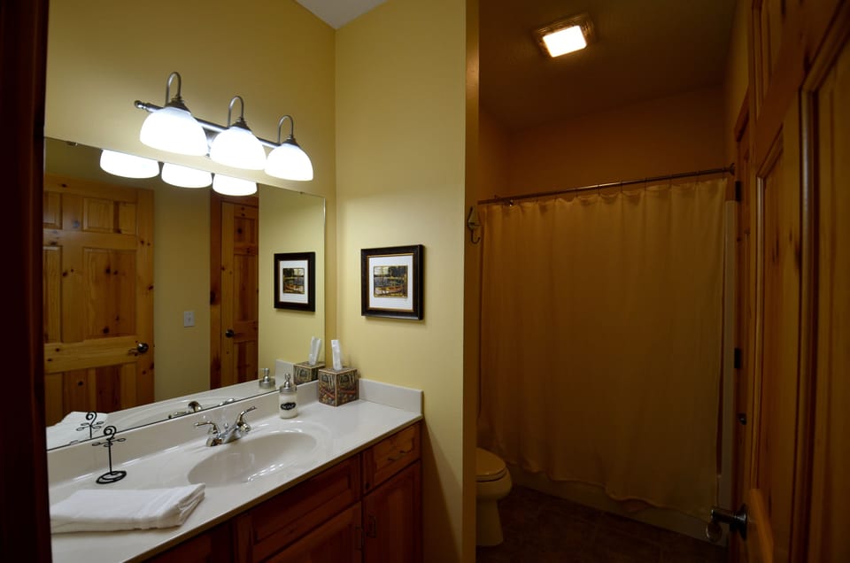 Main floor full bath with heated tile floor and a door to main floor bedroom