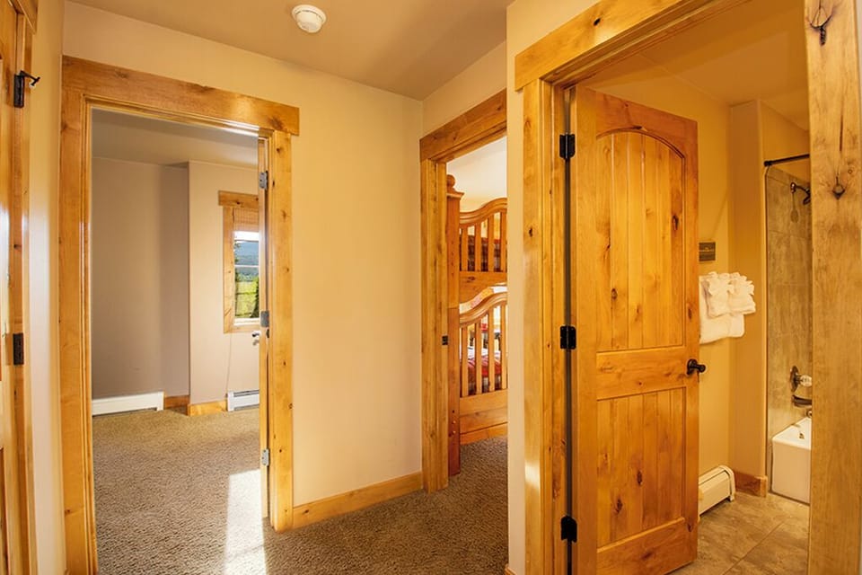 Your rustic hallway connects cozy spaces with warm wood accents and mountain views beckoning through doorways.