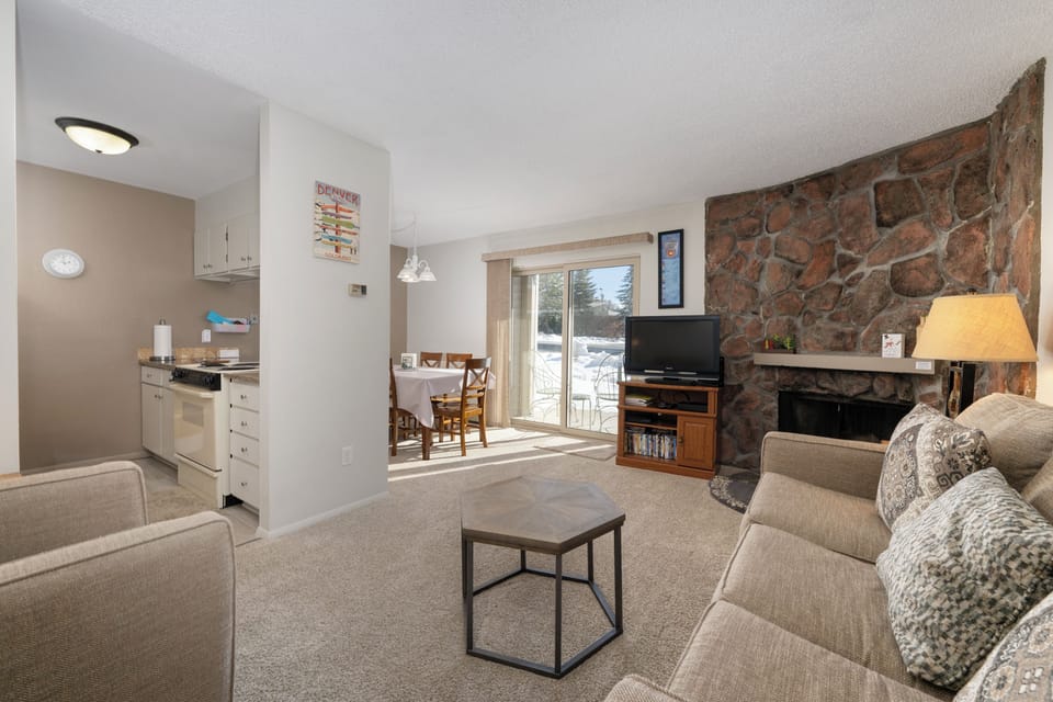 Relax in your cozy mountain retreat with a stunning stone fireplace, open kitchen, and comfortable seating perfect for unwinding after adventure.