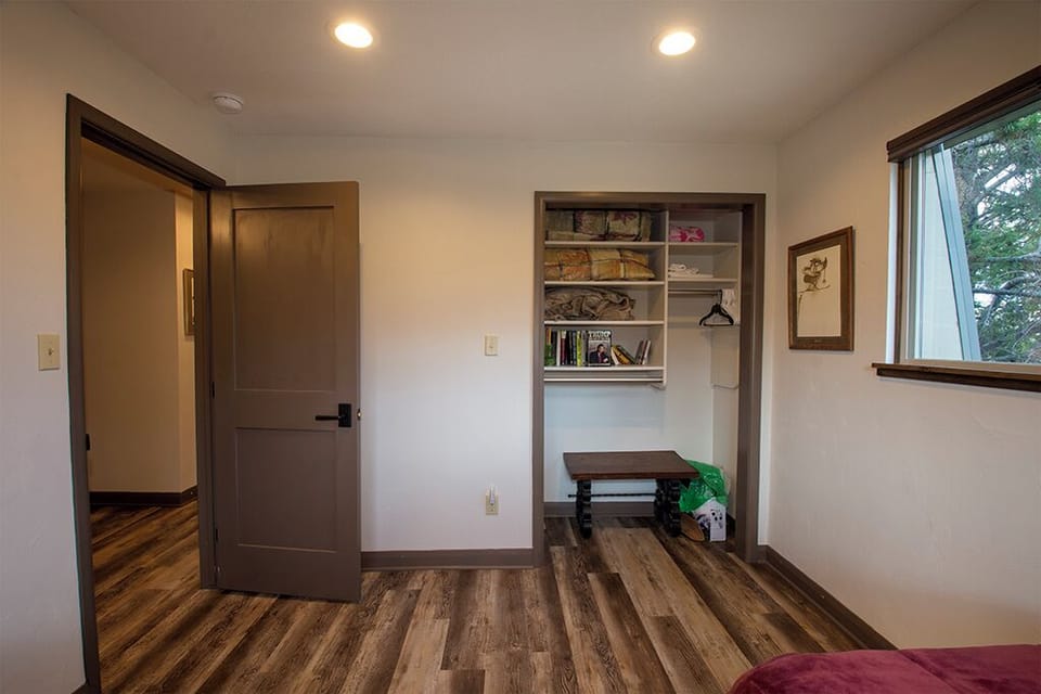 Your cozy bedroom features warm wood floors, built-in storage nook with books, and peaceful natural light for restful nights.