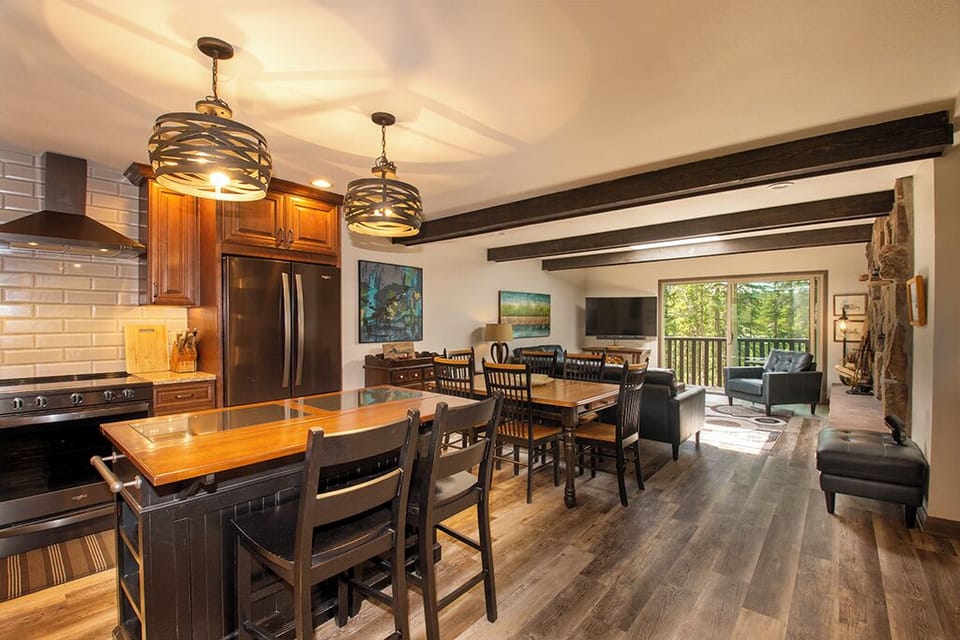 Gather around your spacious kitchen island or cozy up by the stone fireplace in this warm, open-concept living space with forest views.