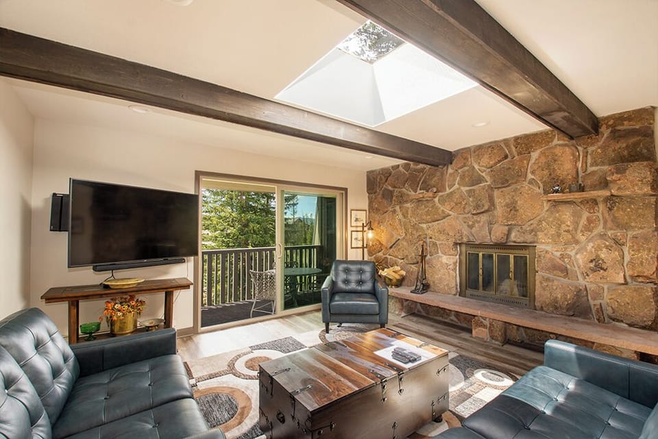 Relax in your stunning living room with exposed beams, stone fireplace, and natural light streaming through the skylight above.