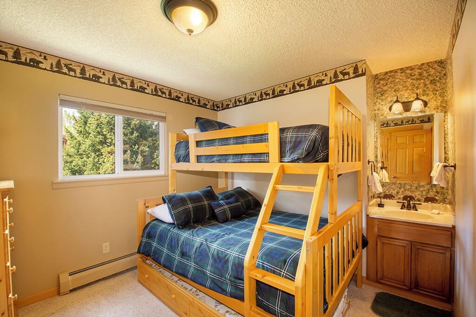 Your rustic bunk room features cozy plaid bedding and an en-suite bathroom, perfect for family adventures.