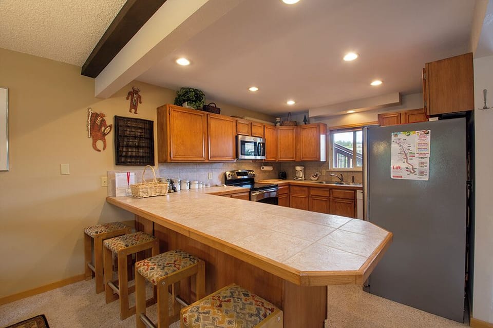 Your fully equipped kitchen features warm wood cabinets, granite counters, and a breakfast bar where you can gather for morning coffee.