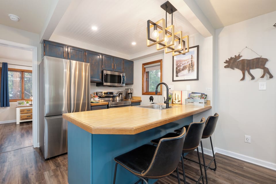 Your fully equipped kitchen features stainless steel appliances, warm wood countertops, and a cozy breakfast bar perfect for morning coffee or evening conversations.