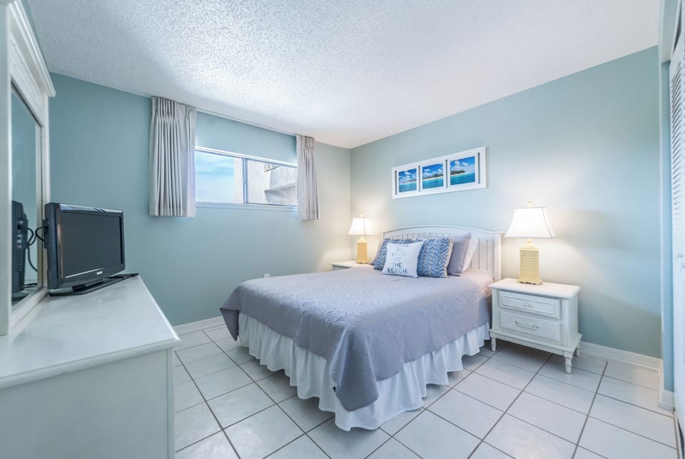 Calming guest bedroom featuring a king bed, closet, and TV.