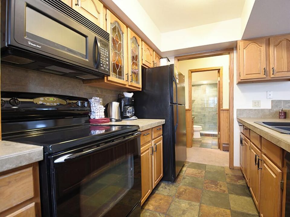 Your fully equipped kitchen features warm wood cabinets, modern appliances, and natural stone flooring—perfect for preparing meals in comfort.