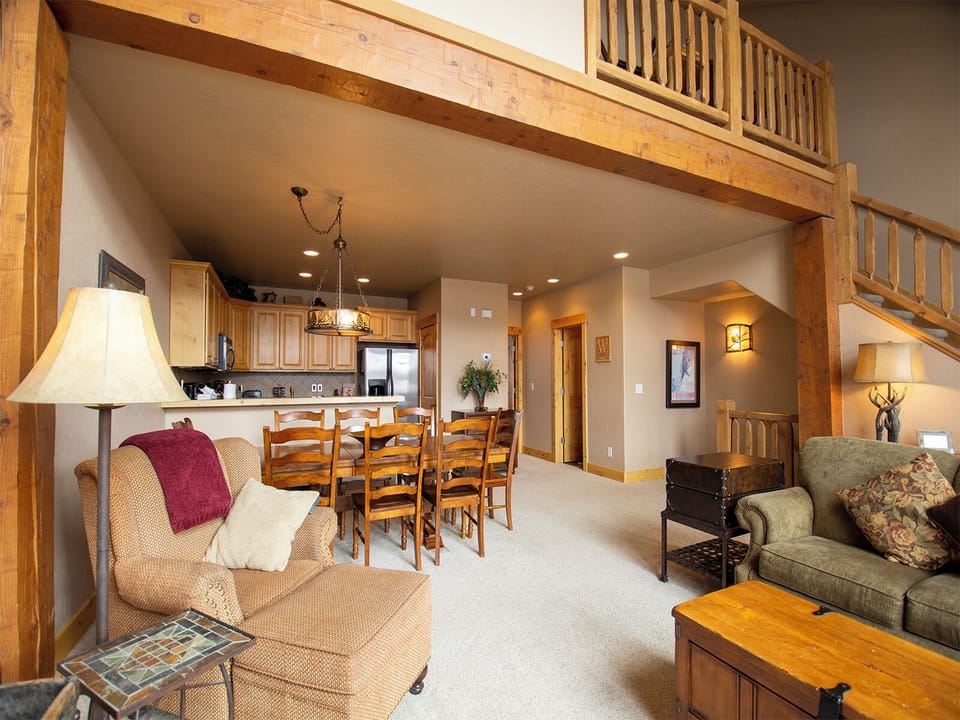 Relax in your spacious loft-style retreat featuring soaring ceilings, rustic wood beams, and a cozy living area that flows into the dining space.