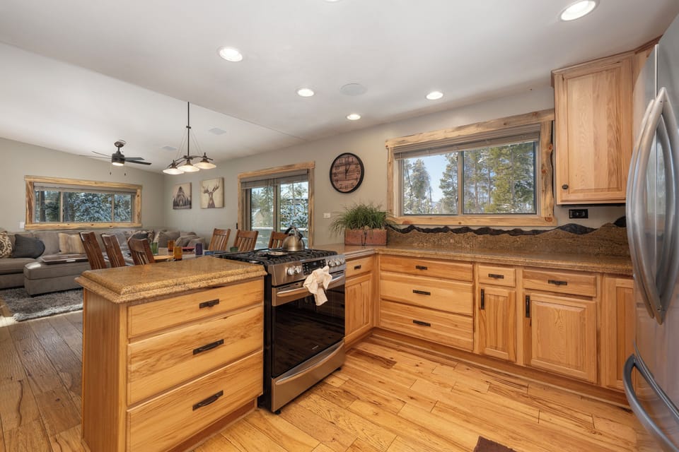Your fully equipped kitchen features granite counters and stainless appliances, perfect for creating meals while enjoying forest views through expansive windows.