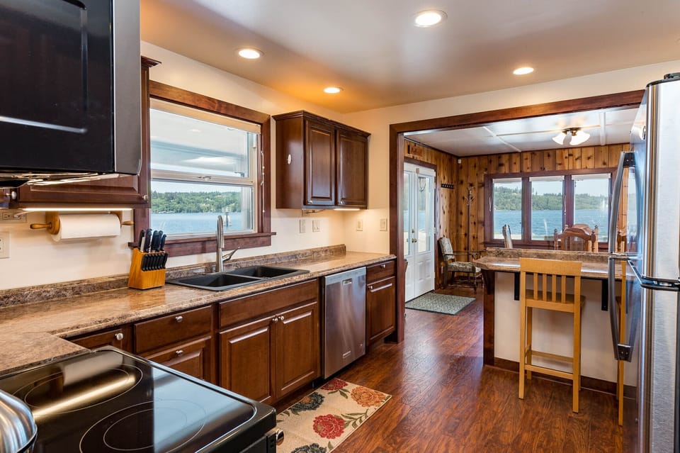 Fully equipped kitchen with counter seating, open to dining/living area. 