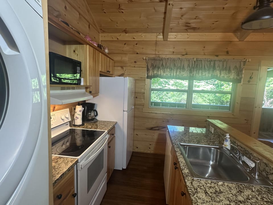Granite countertops stretch across the kitchen, complemented by pine cabinets and a forest-print valance over the window.