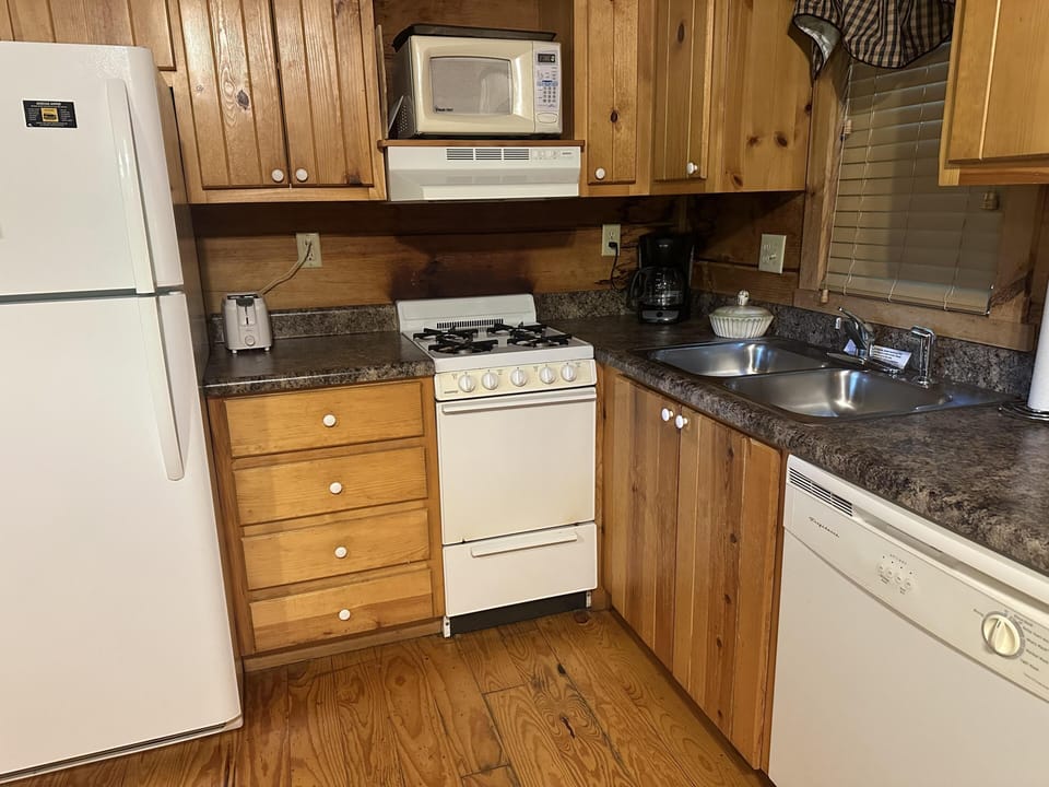 Wood-paneled kitchen with white appliances, granite countertops, double sink, and hardwood floors.