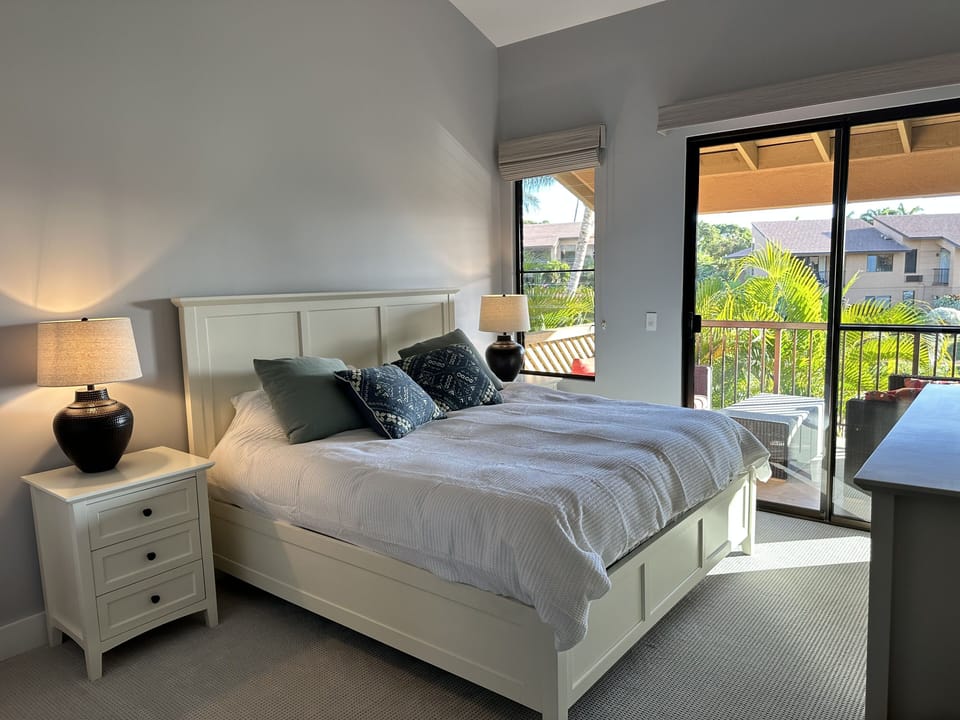 Primary suite with king bed, bath & lanai with ocean and mountain views.