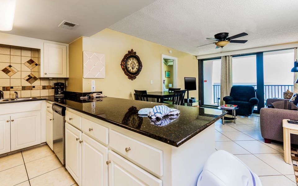 This inviting kitchen features granite countertops, a sleek design, and a view of the beachfront from the living area