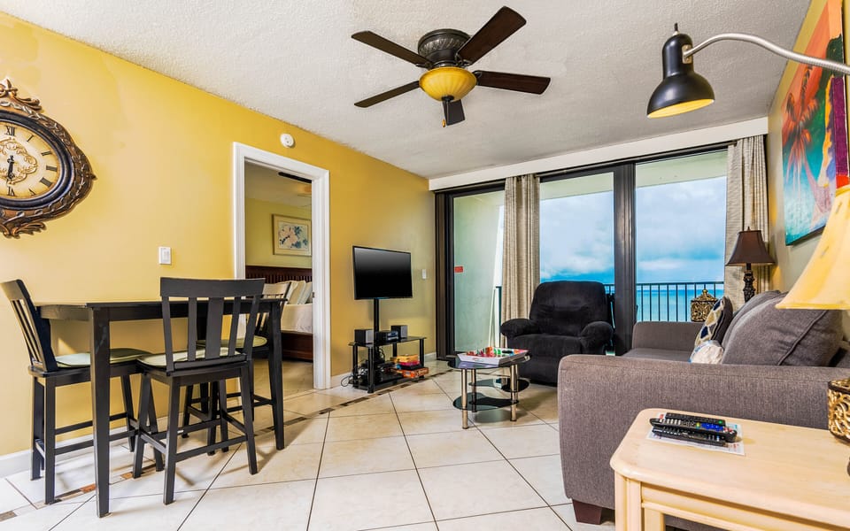 This cozy living area features a TV, a comfortable sofa, and a stunning beachfront view through large sliding glass doors