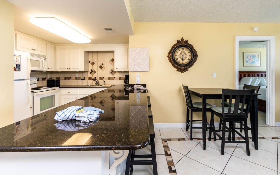 The kitchen features granite countertops, a spacious layout, and a cozy dining area with a view of the adjacent guest bedroom