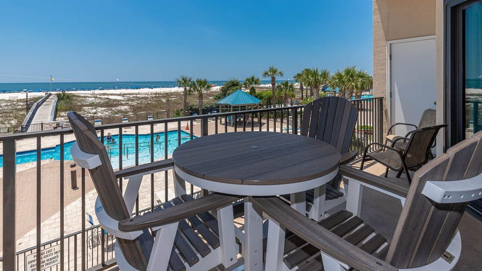 Enjoy a relaxing moment at the outdoor table, overlooking the pool and a beautiful stretch of beach